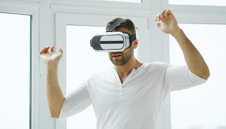 Young man have VR experience with virtual reality headset using hands gestures for control