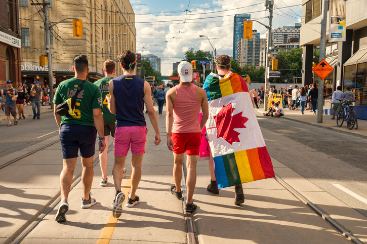 Rear view of a group of five young men walking on Church Street after Pride Parade.