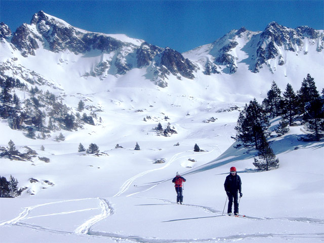 Un valle nevado junto con algunos esquiadores.