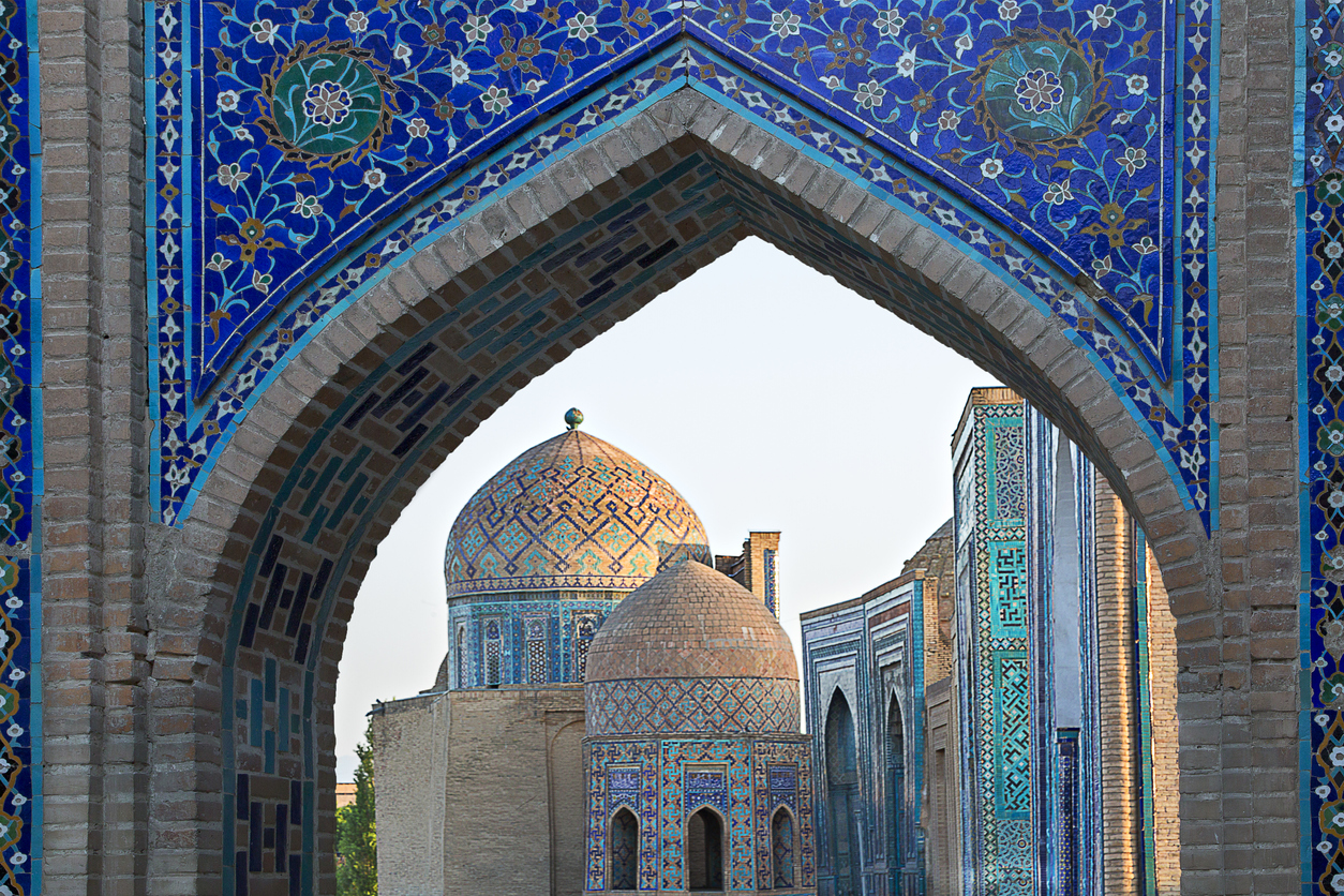 View over the mausoleums and domes of the historical cemetery of Shahi Zinda through an arched gate, Samarkand, Uzbekistan.