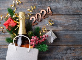 2024 New Year composition. New year holidays card with shopping bag with bottle of hampagne, festive decorations. Gifts, present, festive New Year 2024 background